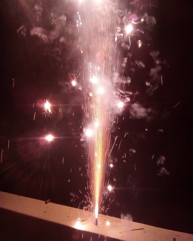 A fountain firework spraying pink and white sparks upwards
