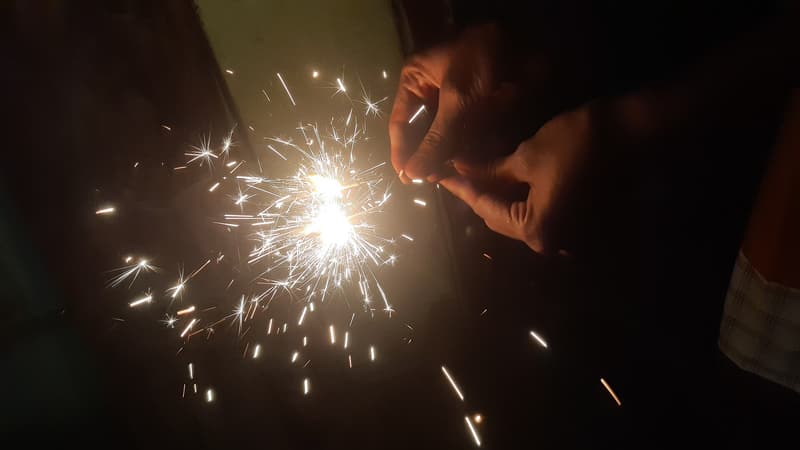 A lit sparkler glowing in the dark